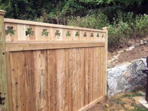 A wood solid panel fence with a top rail that has clover cutouts.